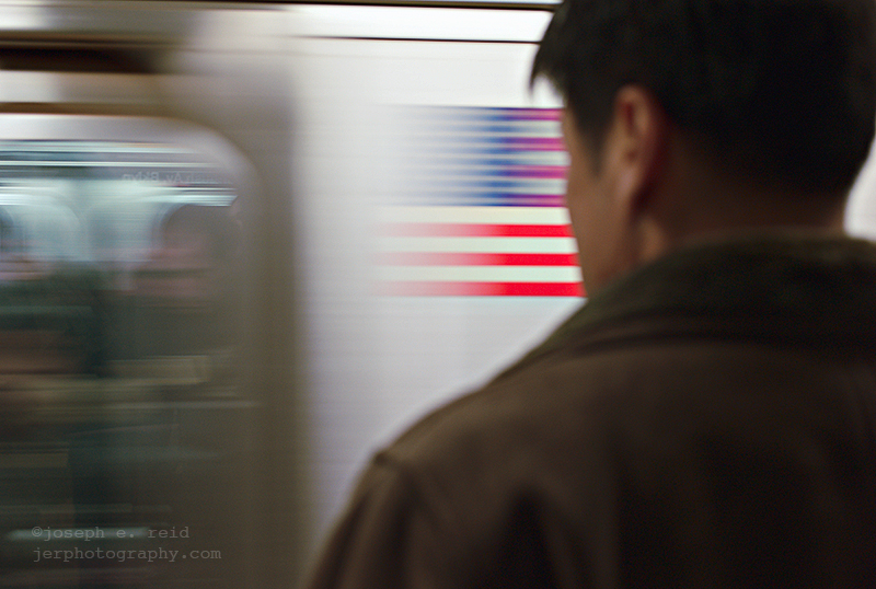080221144 Man watching speeding subway train with image of American flag